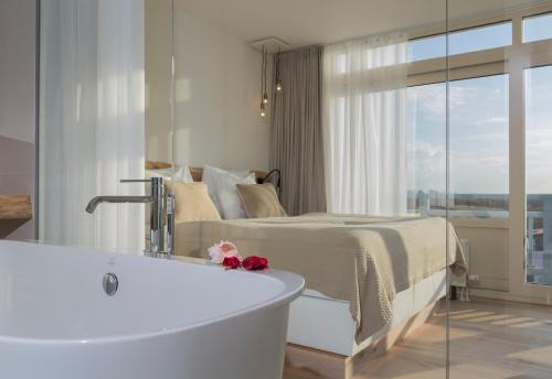 ein Badezimmer mit einer Badewanne neben einem Bett in der Unterkunft Noordzee, Hotel & Spa in Cadzand-Bad