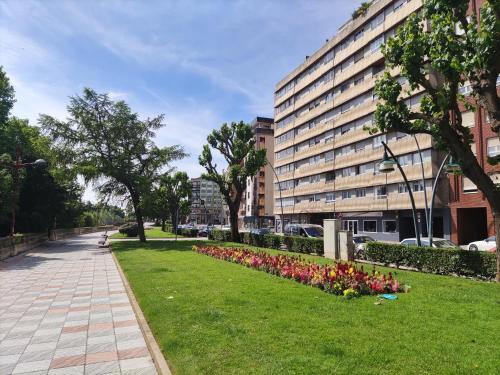 a park with flowers in the grass next to a building at Leon Riverside Flat in León