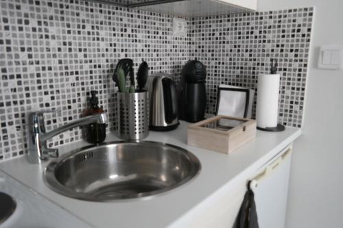 a kitchen counter with a stainless steel sink and a tile wall at Wonder studio apartment prime location and commute in the heart of Kallio in Helsinki
