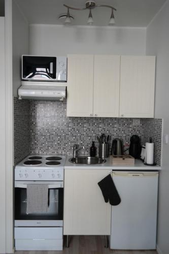 a white kitchen with a stove and a microwave at Wonder studio apartment prime location and commute in the heart of Kallio in Helsinki