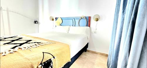 a white bedroom with a bed with a blue headboard at Casa Bakara Vejer old town in Vejer de la Frontera