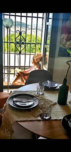 a table with plates and a woman sitting on a balcony at Casa Bakara Vejer old town in Vejer de la Frontera