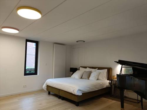 a white bedroom with a bed and a piano at 100% Vacation feeling by the Waterside: Pian'Eau in Ghent