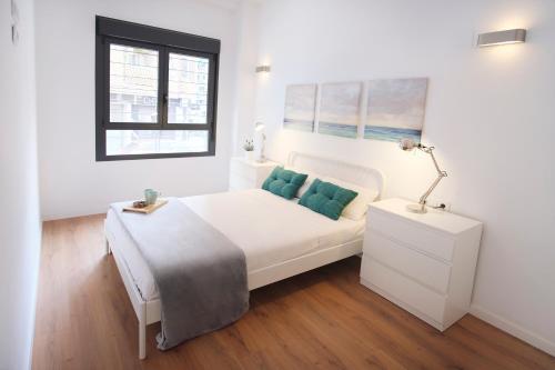 a white bedroom with a white bed and a window at Hogar moderno cerca de Casco Antiguo de Valencia in Valencia