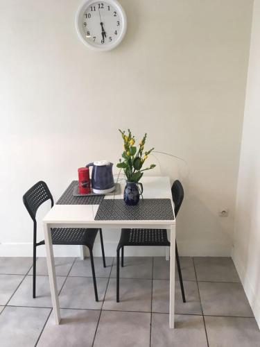 une table blanche avec des chaises et une horloge sur un mur dans l'établissement ANTONY Centre à 150m du RER Antony, des commerces et du marché., à Antony