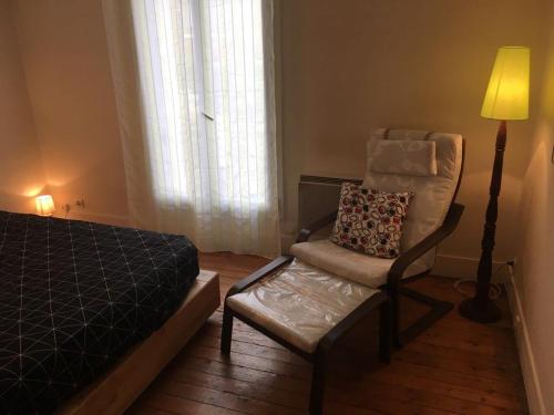 a bedroom with a bed and a chair and a lamp at ANTONY Centre à 150m du RER Antony, des commerces et du marché. in Antony
