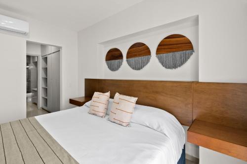 a bedroom with a white bed with a wooden headboard at Casa Barros Vacation Condos in Mazatlán