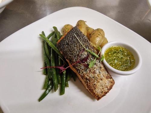 a white plate with a fish and vegetables and a sauce at Portsonachan Hotel & Lodges in Dalmally