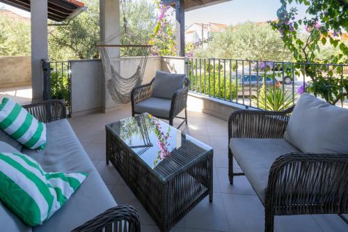 eine Terrasse mit Korbmöbeln sowie einem Tisch und Stühlen in der Unterkunft Lumaja luxury apartman in Biograd na Moru