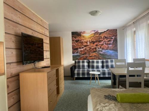 a living room with a bed and a tv on a wall at Pension Sima in Harrachov