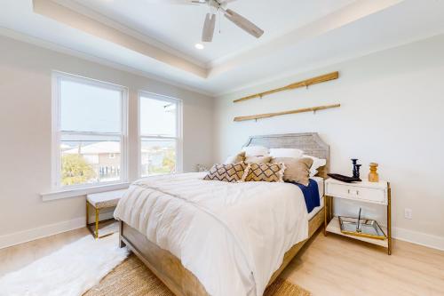 ein weißes Schlafzimmer mit einem Bett und einem Fenster in der Unterkunft Cadillac Margarita in Dauphin Island