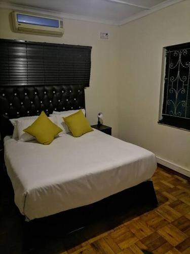 a bedroom with a large white bed with yellow pillows at Prosam Guesthouse Inn in New Germany