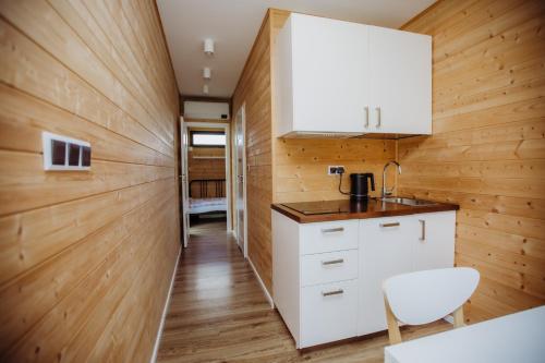 a kitchen with wooden walls and white cabinets at Kontenery Kapalica 
