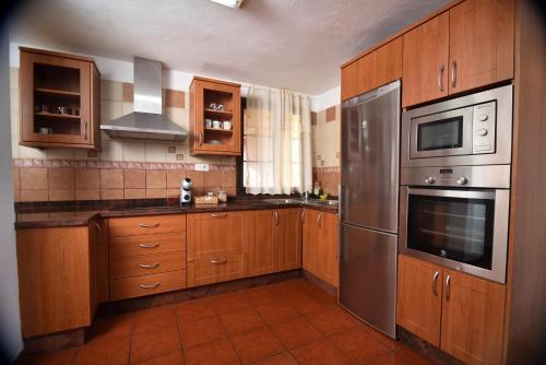 una cocina con armarios de madera y electrodomésticos de acero inoxidable en La Casa de Las Flores, en Tacoronte