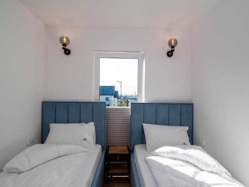 two beds in a room with a window at Ostoja Colette in Jarosławiec