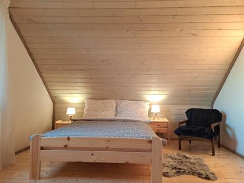 a bedroom with a bed and a chair in a attic at Przystanek Dadaj in Najdymowo