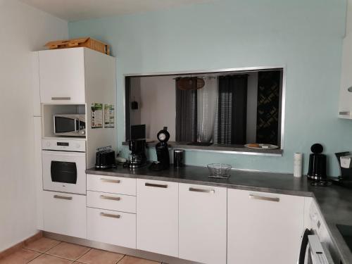 une cuisine avec des armoires blanches et un comptoir dans l'établissement Rez Haut de villa à Calenzana, à Calenzana