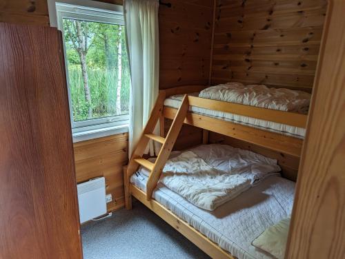 a bedroom with two bunk beds and a window at Solstrand Camping in Vigeland