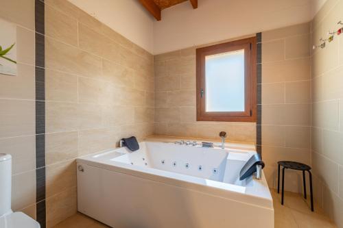 a bathroom with a white tub and a window at Finca Es Figueral in Campos