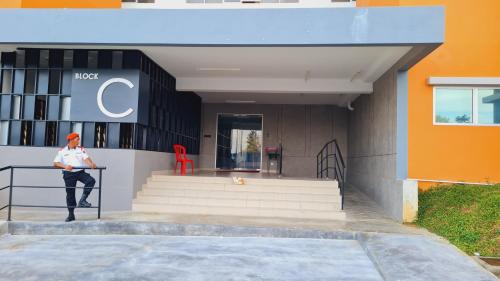 a man sitting on a railing in front of a building at Alanis Suite KLIA With Neflix in Sepang