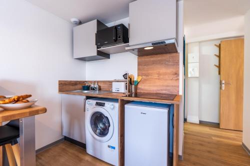 a small kitchen with a washer and dryer at Le Roqueprins - Netflix/Wi-Fi Fibre/Terrasse in Banassac
