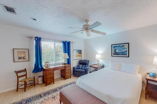 a bedroom with a bed and a desk and a ceiling fan at Tranquility Base in Galveston