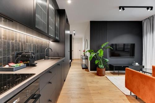 uma cozinha com armários pretos e piso em madeira em Downtown Apartments DOKI Living - Foodhall & Parking em Gdansk