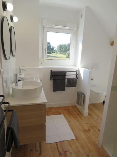 une salle de bain blanche avec un lavabo et une fenêtre dans l'établissement Maison - plage à pied, à Fréhel