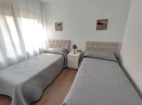two beds sitting in a room with a window at Amplio apartamento con piscina al lado de la playa in Platja d'Aro