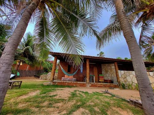 a house with two palm trees in front of it at Suíte pé na areia in Icapuí