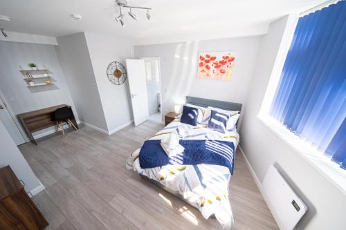 um quarto com uma cama com lençóis azuis e brancos em Stylish Studios with Ensuite, Separate Kitchen, and Prime Location in St Helen em Saint Helens