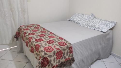uma cama com um cobertor vermelho e branco em 102 Apartamento em Aracruz ES em Aracruz