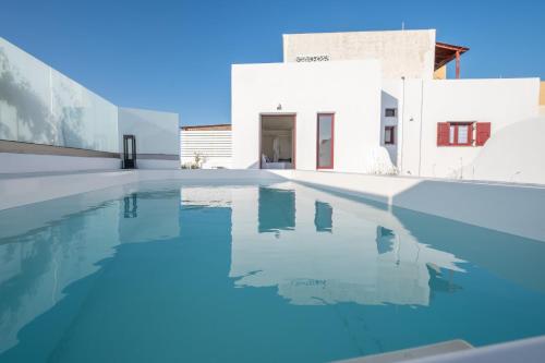 a swimming pool in front of a white building at OUTOPOIA CAVE STUDIOS in Oia