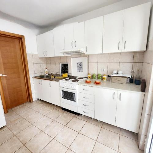 a white kitchen with white cabinets and appliances at A step to the sea-Na korak do mora-Studio apartments Bela kuća in Rafailovici