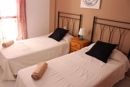 エル・メダノにあるVV El Médano Surのベッドルーム1室(白いシーツが備わるベッド2台付)