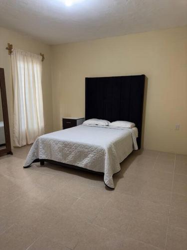 um quarto com uma cama grande e uma cabeceira preta em Departamento completo, cómodo y cerca del aeropuerto em San Agustin de las Juntas