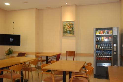 ein Restaurant mit Tischen und einen Kühlschrank mit Getränken in der Unterkunft Apartahotel FC Catedral in León