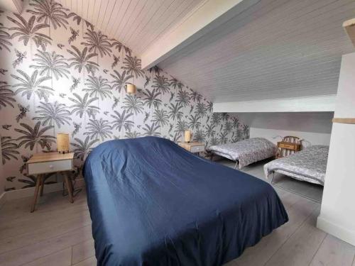 - une chambre avec un lit bleu dans une pièce avec du papier peint en palmier dans l'établissement Maison proche des plages Capbreton et Hossegor, à Bénesse-Maremne