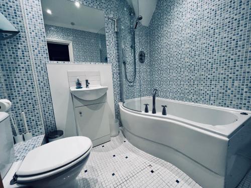 een badkamer met een toilet, een bad en een wastafel bij Bright and Breezy in Portsmouth