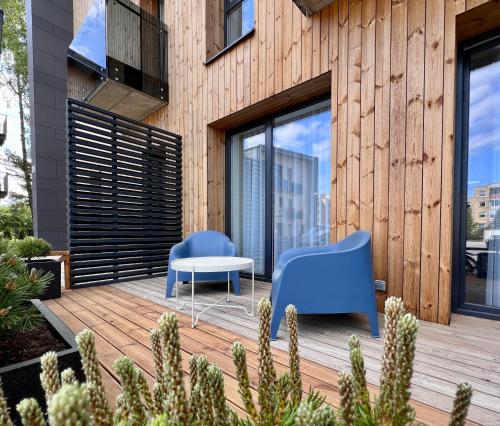 two blue chairs and a table on a wooden deck at TideHaven in Palanga