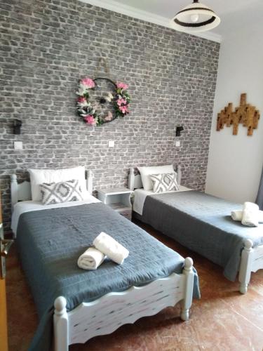 a bedroom with two beds and a brick wall at Teo & Niki in Paleokastritsa