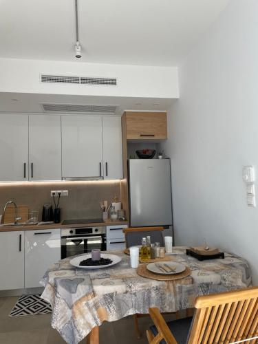 a kitchen with a table and chairs and a kitchen with white cabinets at Μοντέρνα εξοχική μονοκατοικία με ιδιωτική πισίνα! in Khalkoútsion