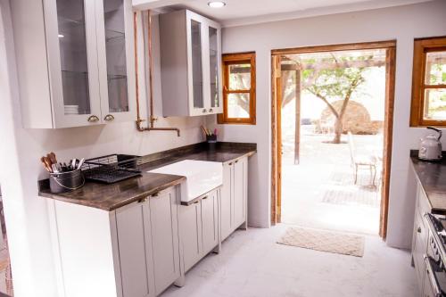 eine Küche mit weißen Schränken und einem Waschbecken in der Unterkunft Compass View in Nieu-Bethesda
