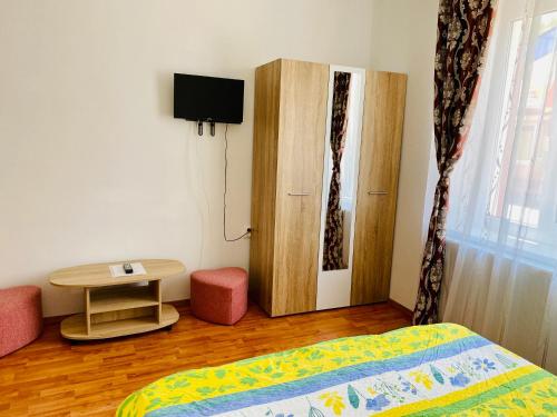 a bedroom with a bed and a table and a cabinet at Casa Victoria in Cârțișoara