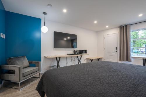 1 dormitorio con cama, silla y escritorio en Le 2020 Charlevoix, en La Malbaie