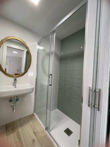 y baño con ducha, lavabo y espejo. en Apartamento turístico Ático La Piterilla en Huelva