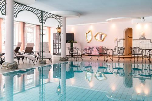 a swimming pool with chairs and tables in a building at Berghotel Hochfügen in Hochfugen