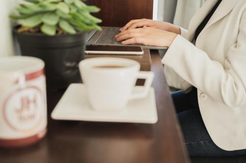 a woman sitting at a table with a laptop and a cup of coffee at JH Hotel Tlatlauqui in Tlatlauquitepec