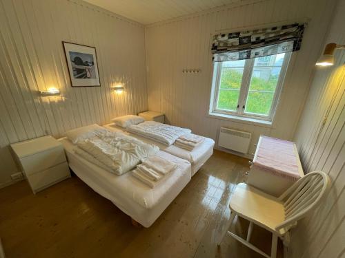 a bedroom with two beds and a window and a chair at Stasjonen - Sørvågen in Moskenes