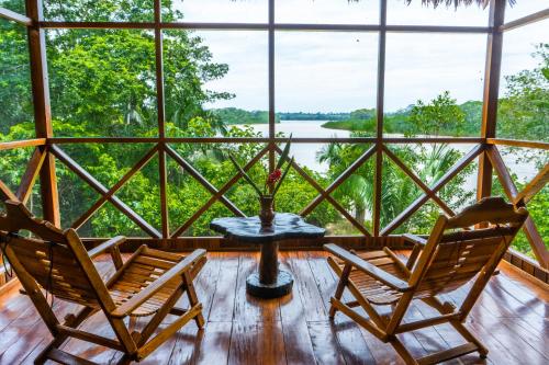 two chairs and a table in a room with windows at Sotupa Eco Lodge in Puerto Maldonado